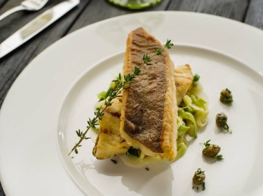 Beyaz tabak haşlanmış pırasa bir yastık üzerine pisi balığı fileto