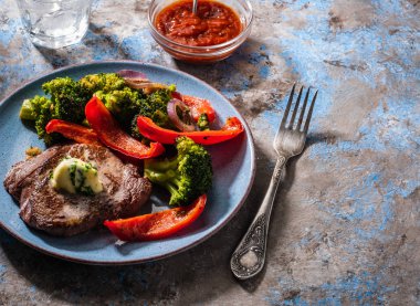 Sarımsak tereyağı ve sebze ızgara sığır eti biftek. Et ızgara dolmalık biber, brokoli ve soğan ile.