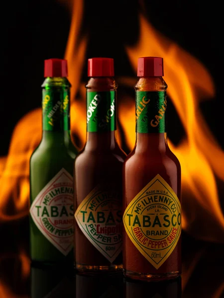 Belarus, Minsk - November 22, 2018: Tabasco sauce bottles with garlick pepper, green pepper and chipotle sauce on fire background