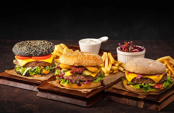 Ahşap Tahtada Üç Sulu Ev Yapımı Beef Cheeseburger. Koyu bir arka plan üzerinde sığır eti ve peynir ile hamburger çeşitleri.