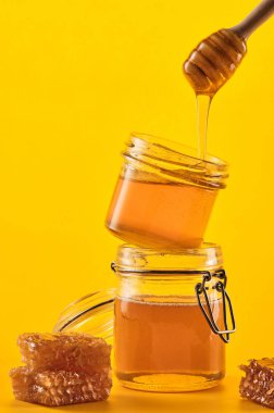 Petekli iki kavanoz bal ve sarı bir backgr üzerinde bir sopa