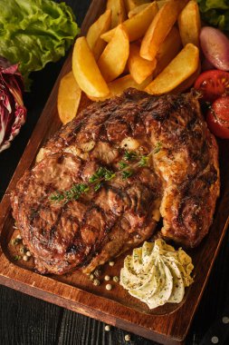 Patates, soğan ve pişmiş kiraz domates ile Ribeye biftek. Ju