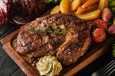 Patates, soğan ve pişmiş kiraz domates ile Ribeye biftek. Ju