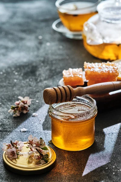 Un borcan de miere cu fagure de miere și un băț, un ceainic cu o ceașcă — Fotografie, imagine de stoc