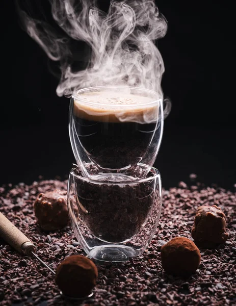 Café Espresso quente em um fundo escuro com grãos de cacau e ca — Fotografia de Stock