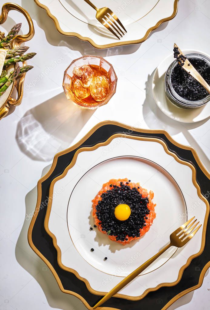 Tartar of salmon with black caviar. Richly laid table in the res