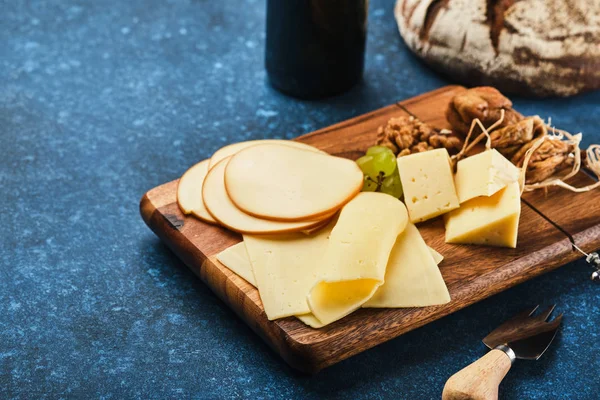 Diferentes variedades de queijo com uvas e nozes em uma lama — Fotografia de Stock