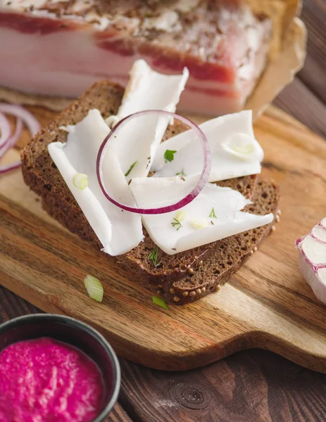 Pork fatback sandwich with onion on wooden board. Rustic style. — Stock Image Pork fatback sandwich with onion on wooden board. Rustic style. Stock Image