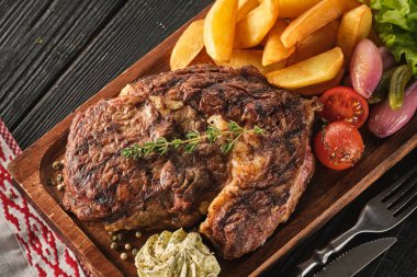 Patates, soğan ve pişmiş kiraz domates ile Ribeye biftek. Ju