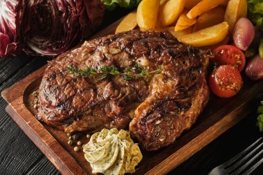 Patates, soğan ve pişmiş kiraz domates ile Ribeye biftek. Ju
