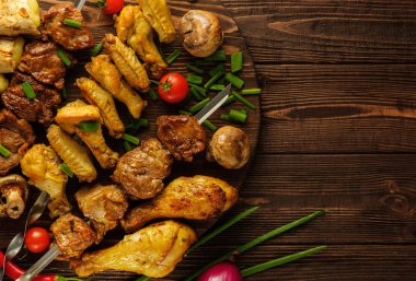 Domates ve gre ile ahşap bir masada tavuk ve sığır şişleri