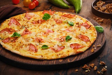 Bir ahşap üzerinde armut, fındık ve pastırma ile lezzetli taze hazırlanmış pizza