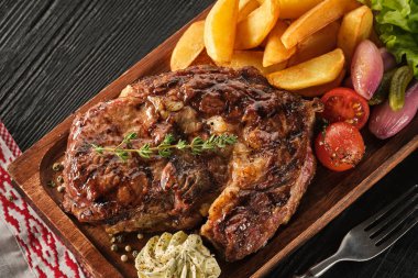Patates, soğan ve pişmiş kiraz domates ile Ribeye biftek. Ju