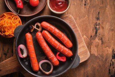 Soğan ve sebze ile bir tavada ızgara sosis