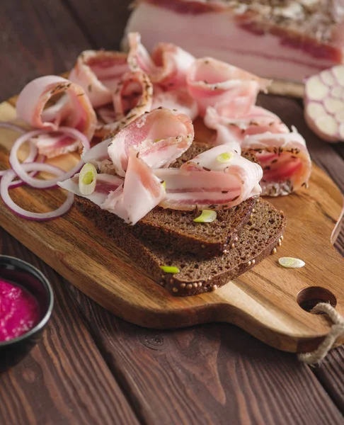 나무 판에 양파와 돼지 고기 지방 샌드위치. 소박한 스타일. — 스톡 사진