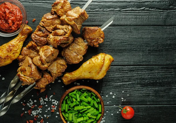 Espetos de frango e carne de vaca em uma mesa de madeira com tomates e gre — Fotografia de Stock