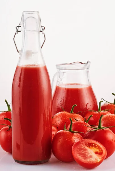 Sabroso jugo de tomate en un vaso con tomates rojos maduros en ba blanca — Foto de Stock