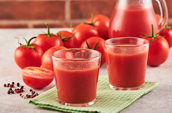 Sabroso jugo de tomate en un vaso con tomates rojos maduros . — Foto de Stock