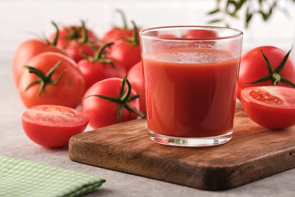 Smaczny sok pomidorowy w szklance z dojrzałymi czerwonymi pomidorami. — Zdjęcie stockowe