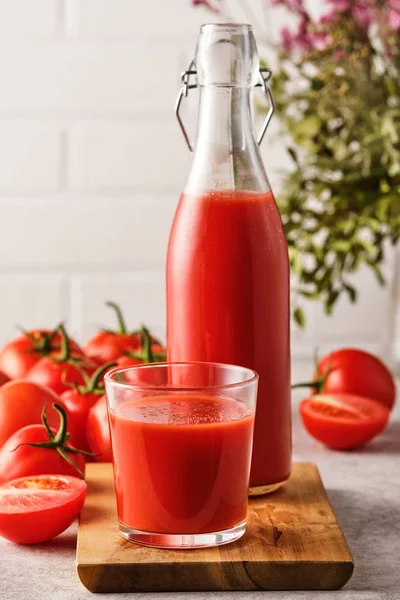 Sabroso jugo de tomate en un vaso con tomates rojos maduros . — Foto de Stock