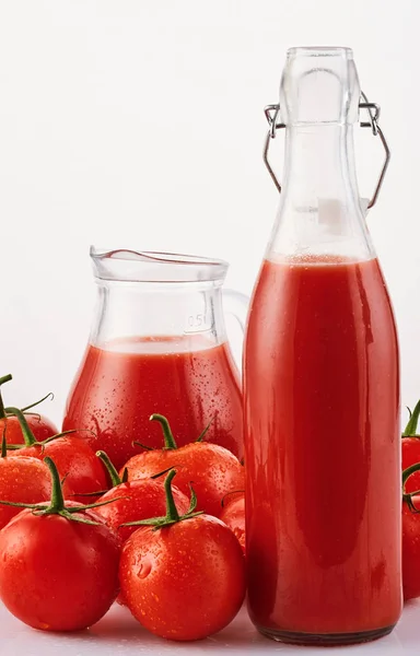 Tasty Tomato juice in a glass with ripe red tomatoes on white ba