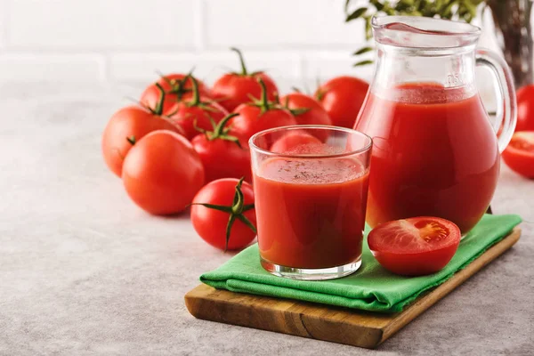 Smaczny sok pomidorowy w szklance z dojrzałymi czerwonymi pomidorami. — Zdjęcie stockowe