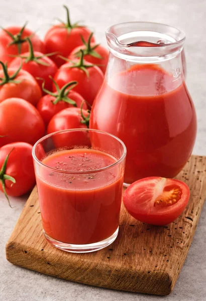 Sabroso jugo de tomate en un vaso con tomates rojos maduros . — Foto de Stock