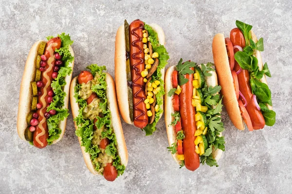 FIve different hot dogs with different toppings on a grey backgr — Stock Photo, Image
