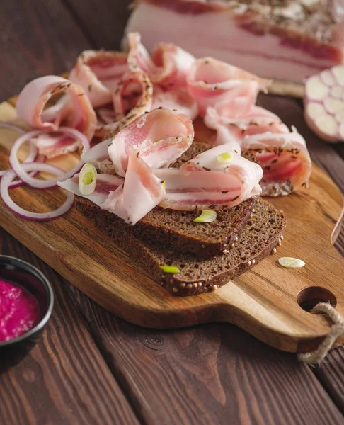 Pork fatback sandwich with onion on wooden board. Rustic style. — Stock Image Pork fatback sandwich with onion on wooden board. Rustic style. Stock Photo