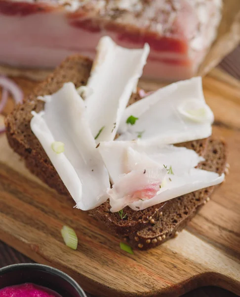 Pork fatback sandwich with onion on wooden board. Rustic style. — Stock Image Pork fatback sandwich with onion on wooden board. Rustic style. Stock Photo