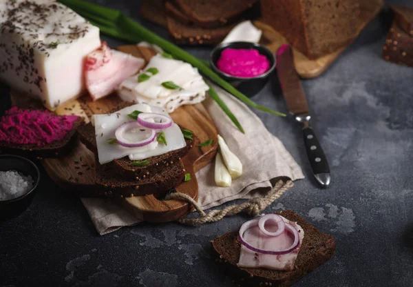 Pork fatback sandwich with onion on wooden board. Rustic style. — Stock Image Pork fatback sandwich with onion on wooden board. Rustic style. Stock Photo