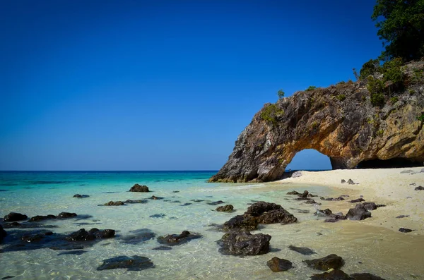 Berrak mavi gökyüzü, açık yeşil ve deniz suyu mavi, sahilde birçok taş, beyaz ve ince kum ve kaya kemer var plaj Satun eyaletinde Koh Kai adanın bir imza, Tayland.