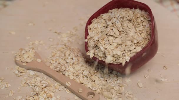 Oat grains are poured into a red bowl. 4k video shot. — Stock Video