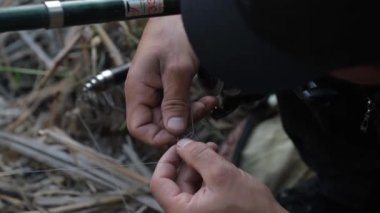 Balıkçı oltaya yem takar. Balıklar için beslenme hazırlığı.