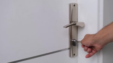 Adam anahtarla odanın kapısını açıyor..