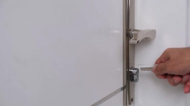 Adam anahtarla odanın kapısını açıyor..
