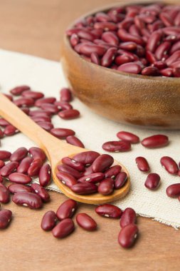 Ahşap kase ve keten ve ahşap zemin üzerine koyarak kaşık kırmızı fasulye.