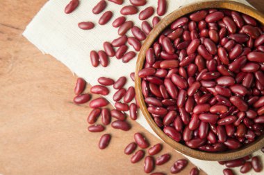 Ahşap kase koyarak keten ve ahşap arka plan üzerinde kırmızı fasulye.