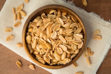 Ahşap kase keten ve ahşap zemin üzerine koymak kavrulmuş fıstık.