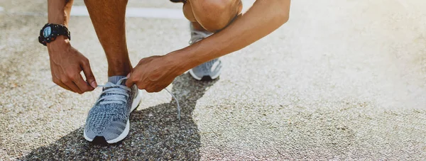 Man tying running shoes getting ready for run. Healthy lifestyle and sport. Banner with copy space.