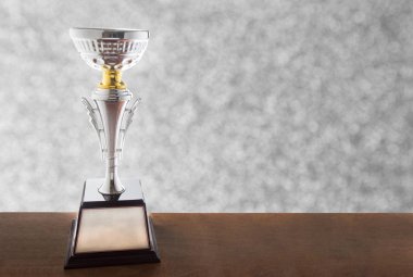 Bokeh arka plan üzerinde ahşap masa üzerinde Gümüş kupa. Kopya alanı ile ödül kazanma.