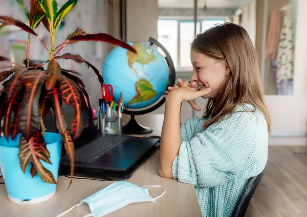 Girl 10 years old in a mask on distance learning at home. The child is bored, he is tired