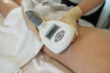 Hemşire, kadın kalçasında lenfatik drenaj aparatıyla manipülasyon yapıyor. Anti-selülit masajı yapıyor.