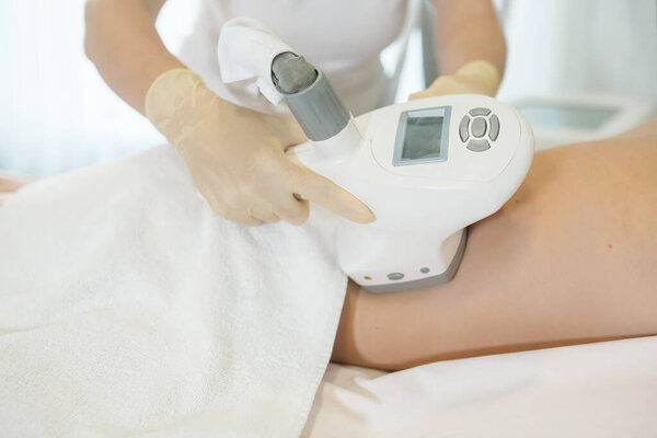 The nurse performs the manipulations with the lymphatic drainage apparatus on the woman hips , doing anti-cellulite massage