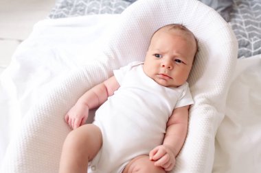 Yeni doğmuş bebek evdeki yatak odasındaki koza üzerinde yatıyor.