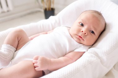 Yeni doğmuş bebek evdeki yatak odasındaki koza üzerinde yatıyor.