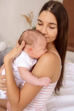 Genç, güzel esmer anne kucağında yeni doğmuş bir bebek tutuyor.