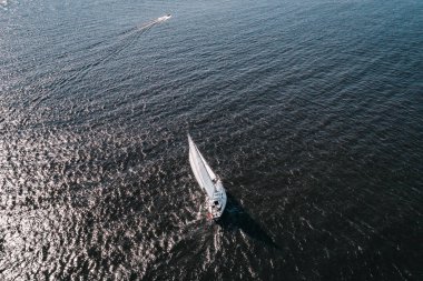 Açık mavi alanda beyaz yelkenli yatın havadan çekilmiş fotoğrafı. Güzel rüzgar güneşli bir yaz gününde yelken açar..