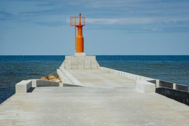 Küçük modern kırmızı deniz feneri direği yenilenmiş beton köstebek mavi gökyüzünde izole.