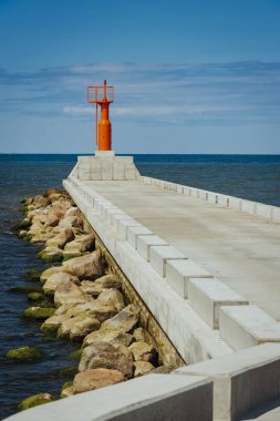 Küçük modern kırmızı deniz feneri direği yenilenmiş beton köstebek mavi gökyüzünde izole.